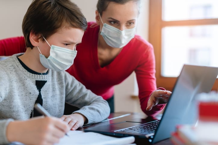 Mother and son in video chat with school teacher wearing masks